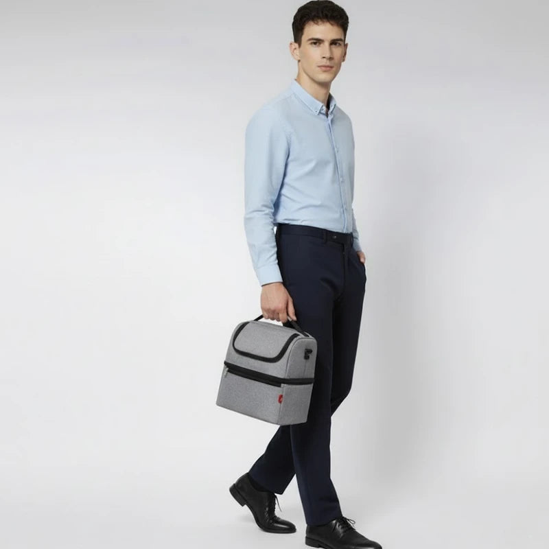 Homme en tenue professionnelle marchant avec un sac isotherme gris tenu à la main.