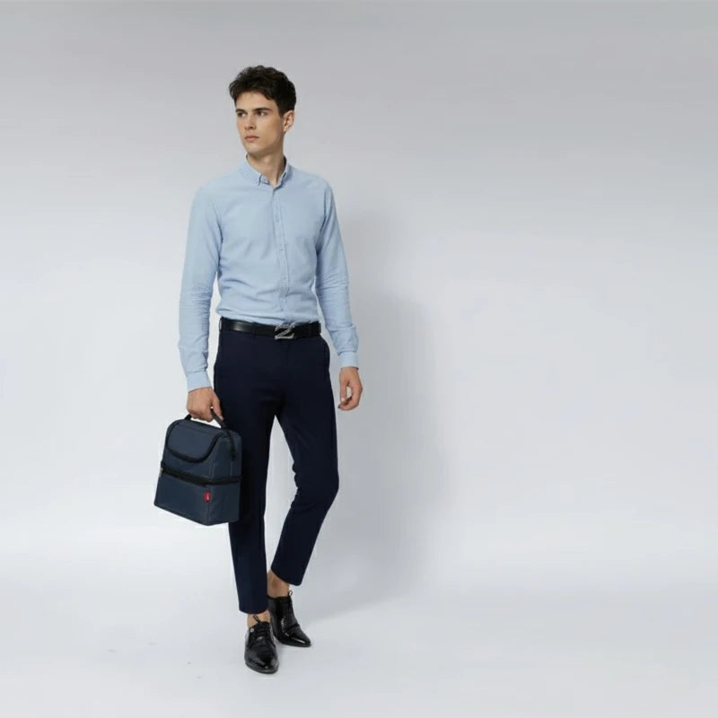 Homme en chemise bleue marchant avec un sac isotherme bleu marine tenu à la main.