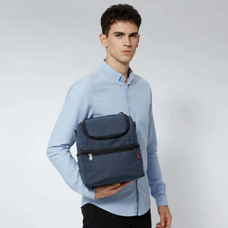 Homme tenant un sac isotherme bleu contre le flanc, en chemise claire et pantalon foncé.
