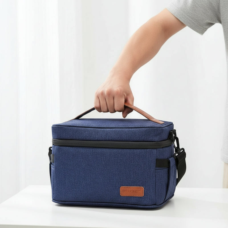Lunch bag isotherme 7L bleu denim tenu à la main, illustrant le transport facile d’un repas frais au bureau ou en déplacement.