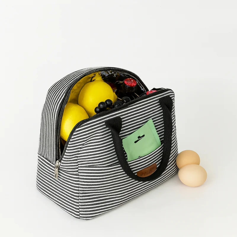 Lunch Bag à rayures noir et blanc ouvert, contenant des citrons, des bouteilles et des raisins, illustrant sa capacité et son isolation thermique efficace.