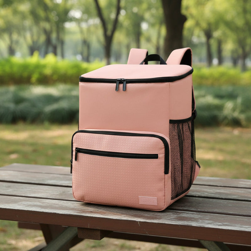 Sac à dos isotherme rose posé sur une table en extérieur, avec grande capacité et poches latérales en filet pour sorties pique-nique ou déplacements.