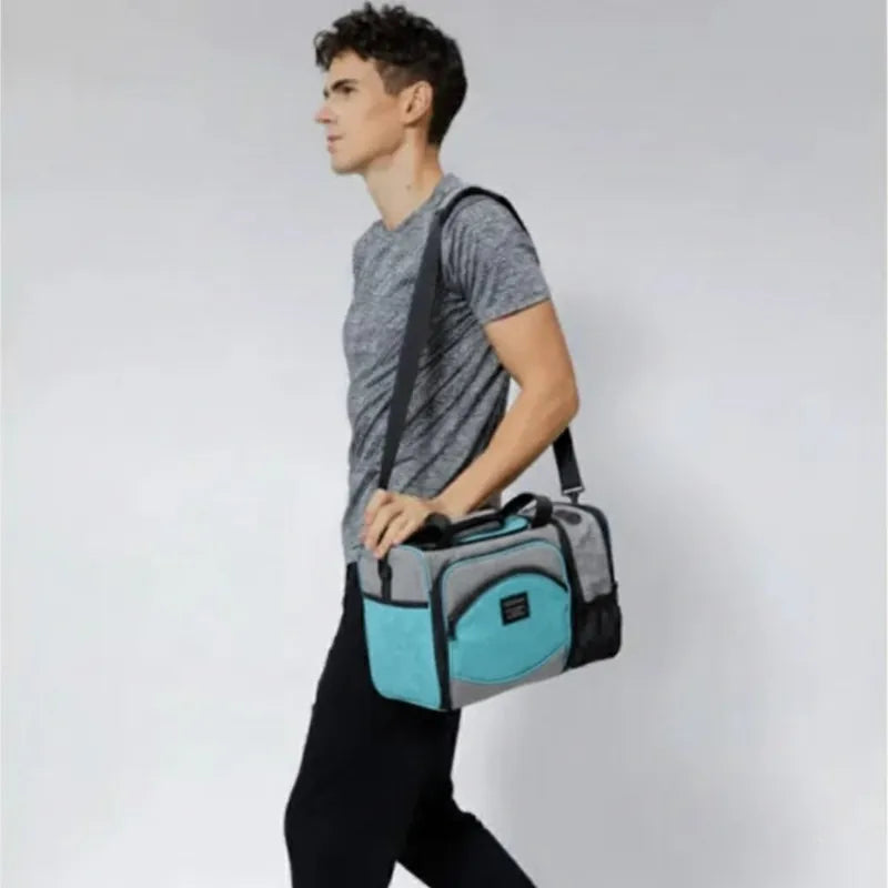 Homme marchant avec un sac isotherme 25L gris et bleu turquoise porté sur l’épaule, idéal pour transporter repas et boissons fraîches.