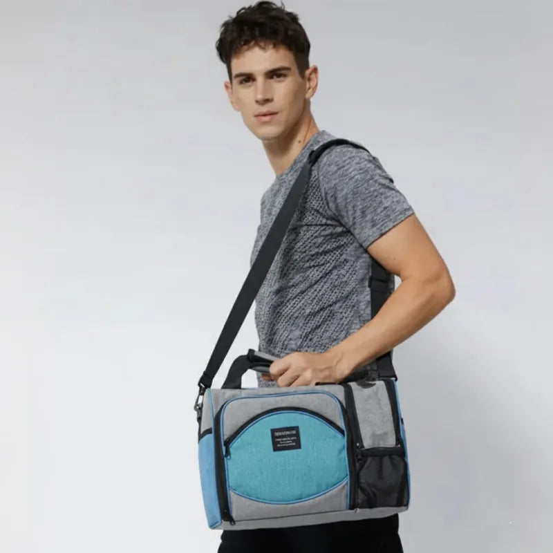 Homme portant un sac isotherme 25L gris et bleu turquoise uni en bandoulière, idéal pour les repas au bureau, les voyages ou les pique-niques.