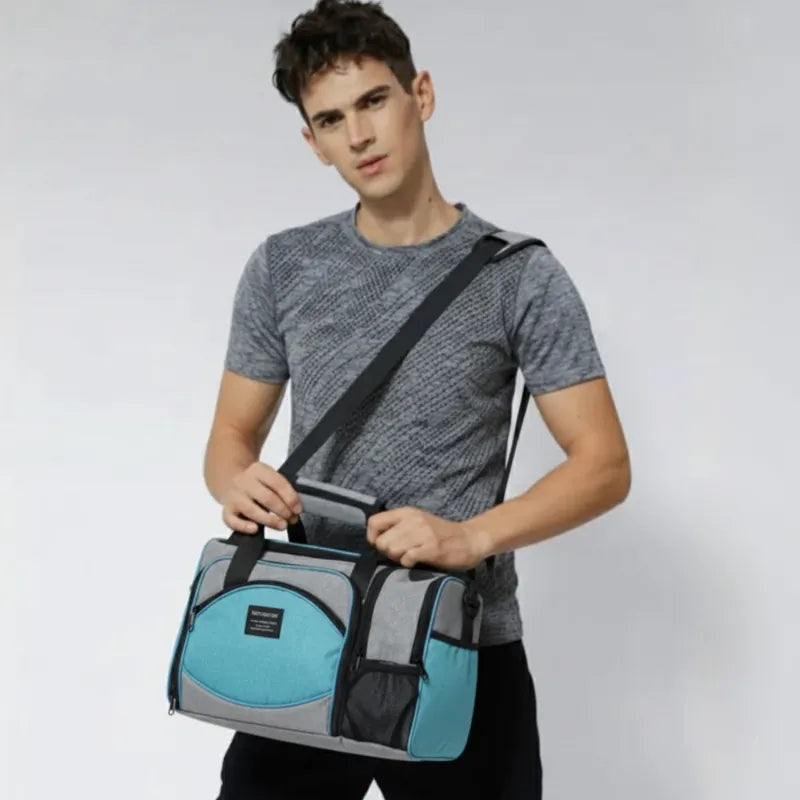 Homme tenant un sac isotherme 25L gris et bleu turquoise uni avec bandoulière, idéal pour transporter des repas ou boissons au frais.