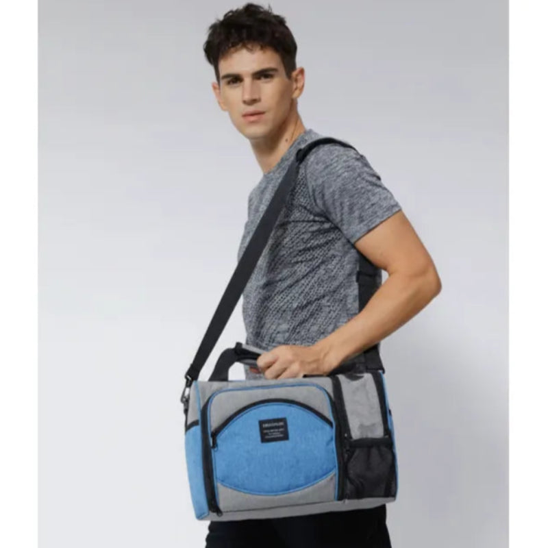 Homme portant un sac isotherme 25L gris et bleu uni sur l’épaule avec bandoulière.