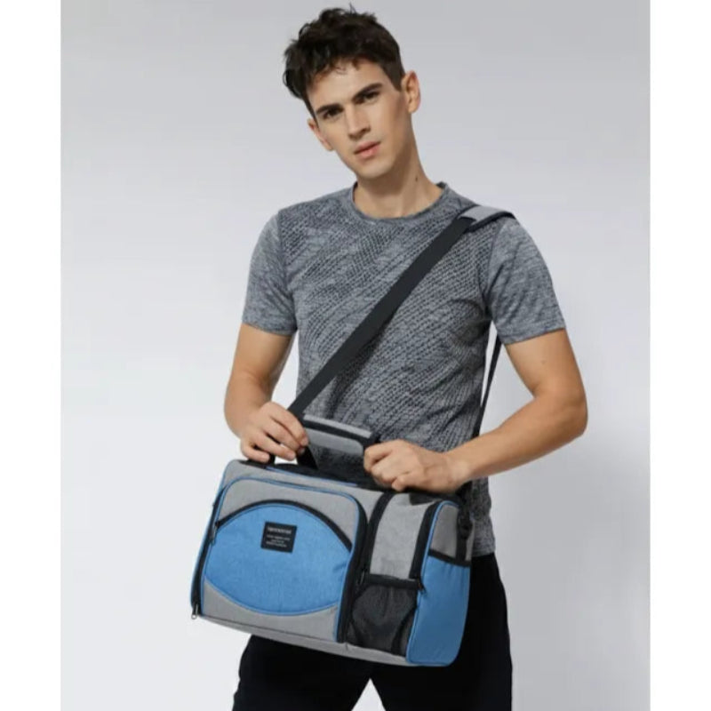 Homme portant un sac isotherme 25L gris et bleu uni à la main avec bandoulière.