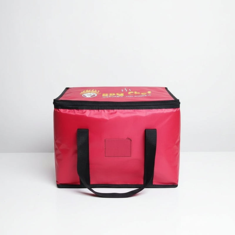 Sac isotherme rouge BBQ Chef vu de face avec poignées noires, posé sur une table blanche, adapté au transport de repas chauds ou froids.