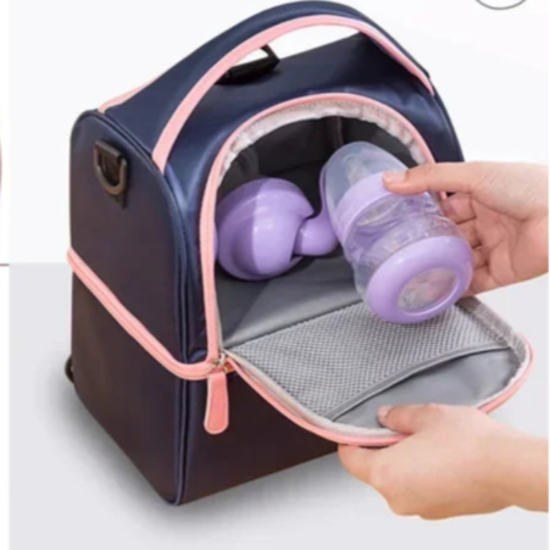 Sac isotherme bébé bleu et rose ouvert contenant deux biberons, avec une main rangeant un biberon dans le compartiment supérieur.