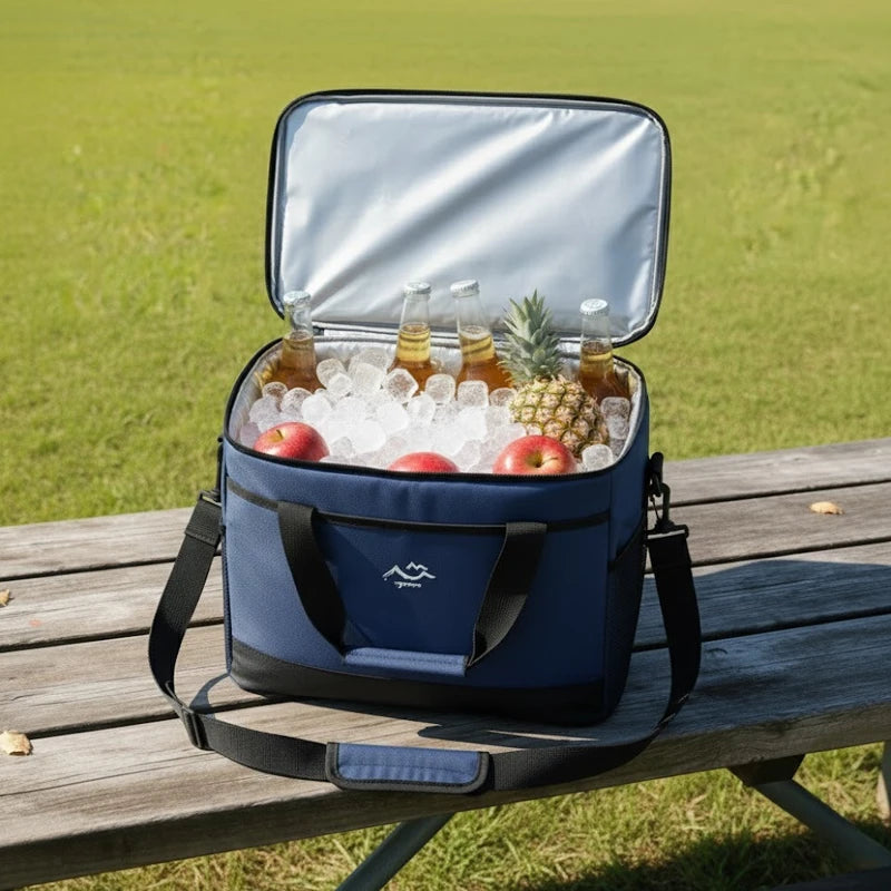 sac isotherme bleu ouvert rempli de glaçons, bouteilles, pommes et ananas, posé sur une table en bois en extérieur