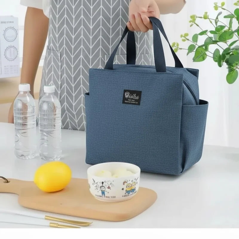 Sac isotherme bleu posé sur une table avec repas et bouteilles, utilisé comme lunch bag pour le bureau