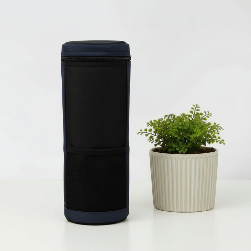 Sac isotherme pour bouteille bleu vu de dos, posé sur une table claire à côté d’une plante décorative.