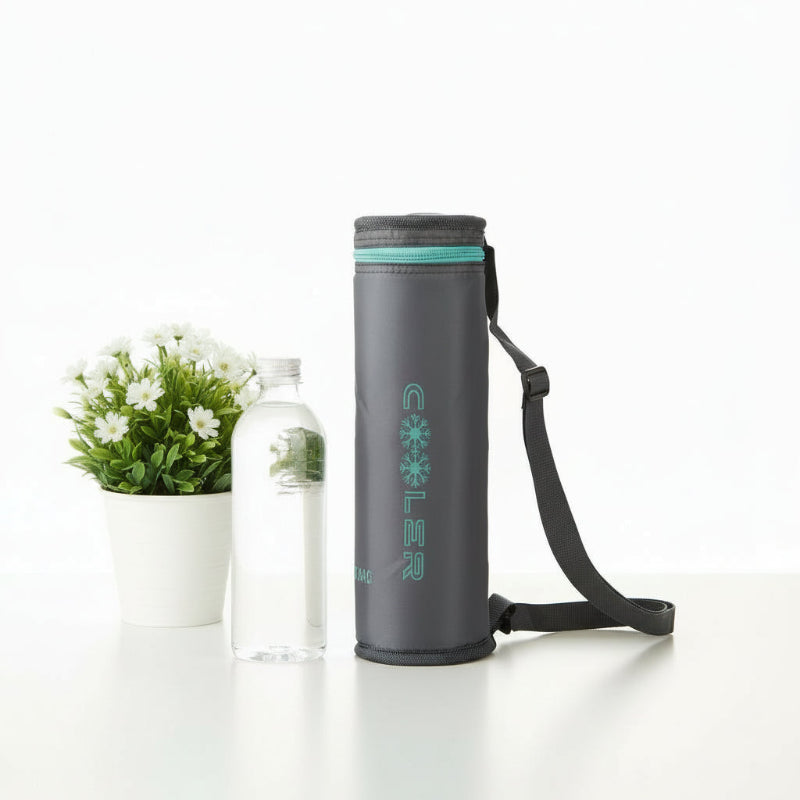 Sac isotherme pour bouteille en gris avec bandoulière, posé sur une table blanche à côté d’une bouteille d’eau et d’une plante.