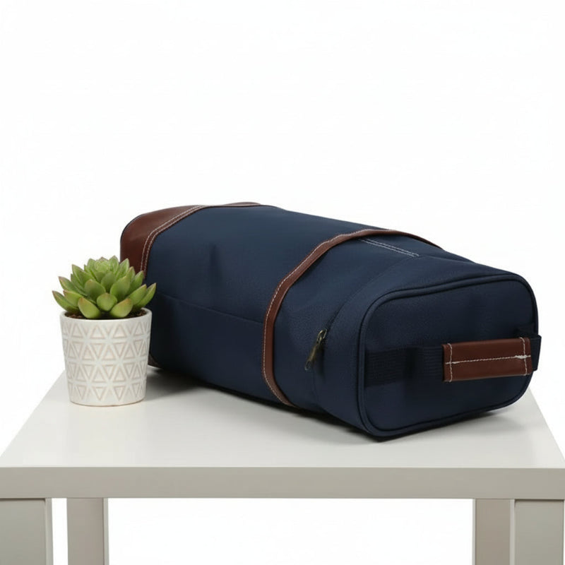 Sac isotherme pour bouteille bleu marine allongé sur une table, vu de dessus, avec une plante décorative à côté.