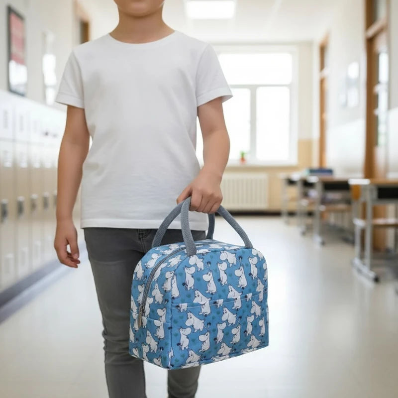 Sac isotherme enfant bleu avec motifs hippopotames, porté à la main dans un couloir d’école, format pratique pour transporter le repas.
