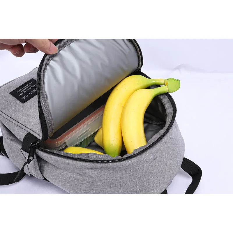 Vue intérieure d’un sac isotherme gris contenant plusieurs bananes et une lunch box.