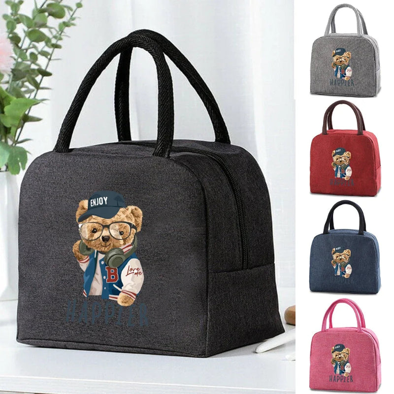 Sac isotherme enfant motif ourson “Happier” présenté en plusieurs couleurs (noir, gris, rouge, bleu, rose), avec une vue principale du modèle noir posé sur une table.