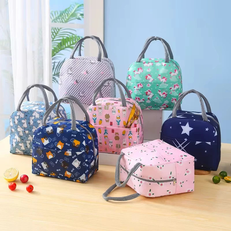 Collection de sacs isothermes pour enfant avec différents motifs colorés, présentés sur une table dans une pièce lumineuse.
