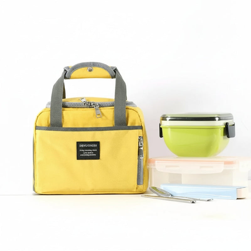 Sac isotherme jaune posé sur une table avec des boîtes repas et des couverts, idéal pour transporter un déjeuner au bureau ou à l’école.