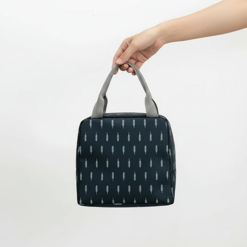 Sac isotherme repas enfant noir avec motif feuilles blanches, tenu par la poignée, format compact adapté aux petits repas.