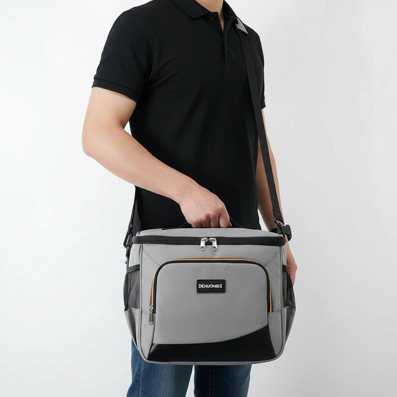 Personne portant un sac isotherme repas gris, tenu par la poignée avec une bandoulière visible, sur fond blanc.