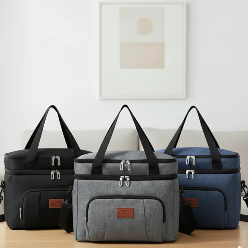 Trois sacs isothermes repas avec bandoulière, en coloris noir, gris et bleu, posés côte à côte sur une table dans un intérieur moderne.