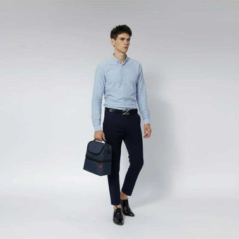 Homme en tenue business marchant avec un sac isotherme bleu tenu à la main.