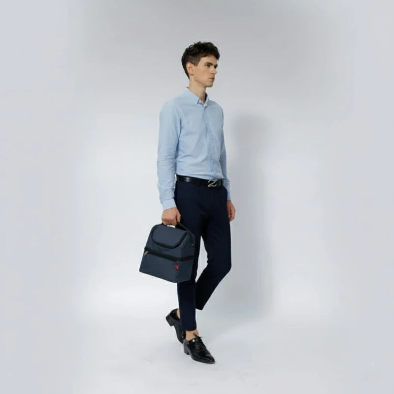 Homme en chemise bleue marchant avec un sac isotherme bleu porté à la main.