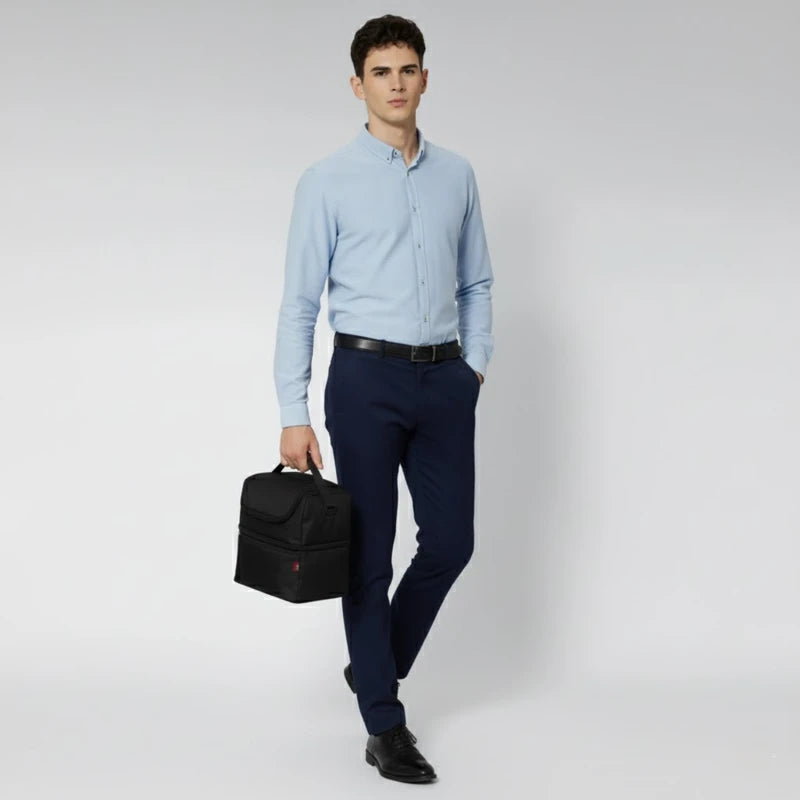 Homme en chemise bleue marchant avec un sac isotherme noir porté à la main.