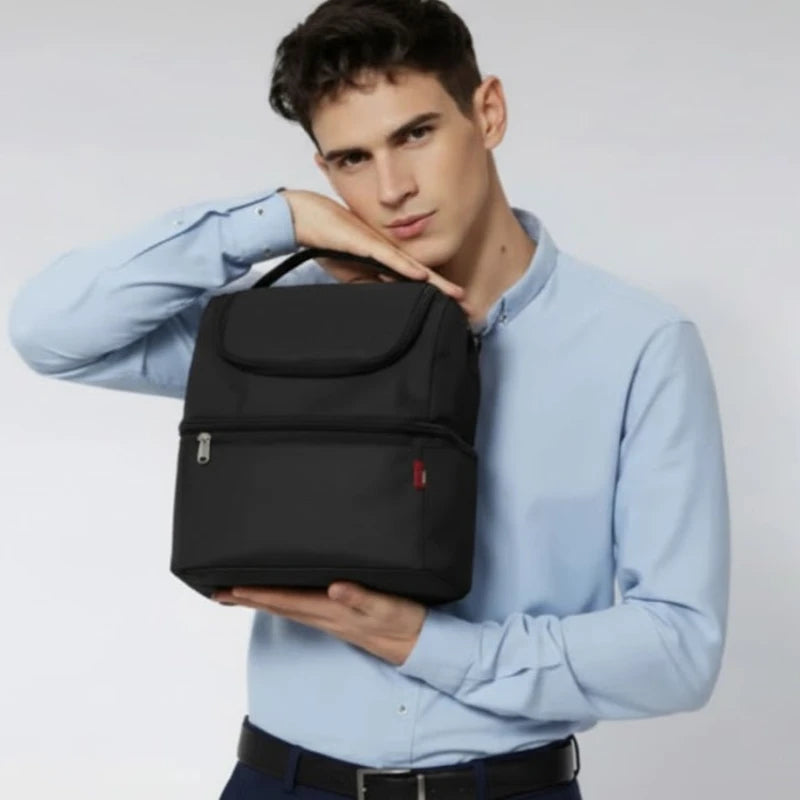 Homme en chemise bleue tenant un sac isotherme noir en gros plan, dans un studio au fond clair