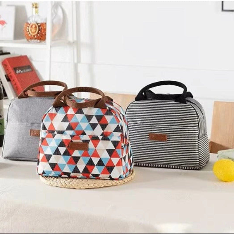 Trois lunch bags isothermes posés sur une table, avec des motifs géométriques colorés, rayures noir et blanc, et gris uni, parfaits pour transporter les repas au quotidien.