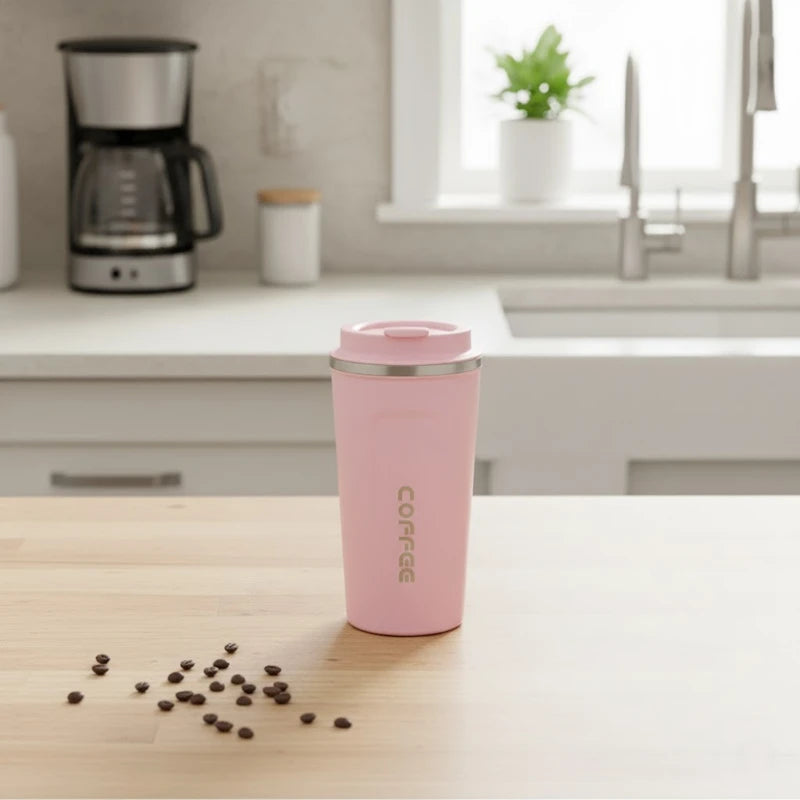 Mug isotherme en inox rose pastel posé sur un plan de travail, parfait pour garder le café ou le thé chaud plusieurs heures.