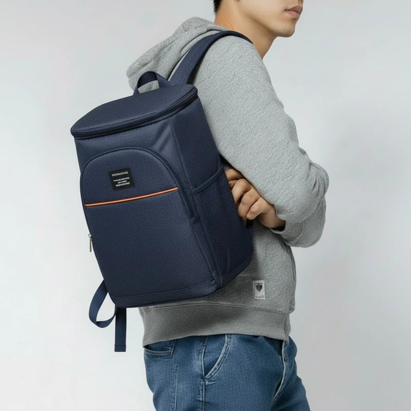 sac à dos isotherme bleu marine porté par un homme en sweat gris, vue de profil, avec poche avant zippée et détail orange