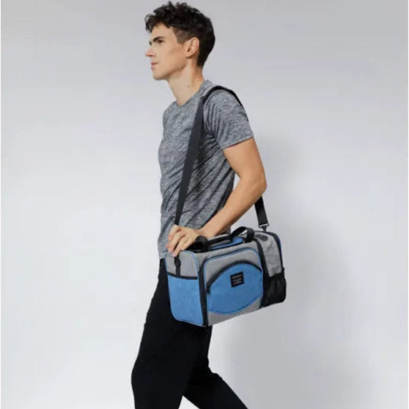 Homme portant un sac isotherme 25L gris et bleu uni en bandoulière.