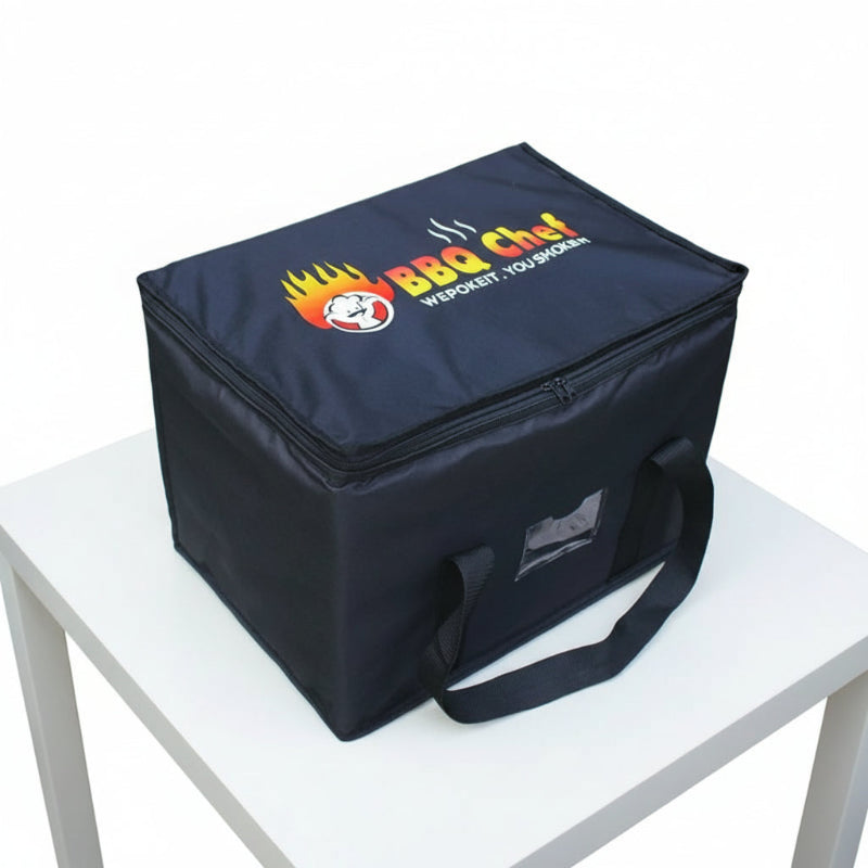 Sac isotherme noir BBQ Chef posé sur une table blanche, vu en angle, avec poignées avant visibles.