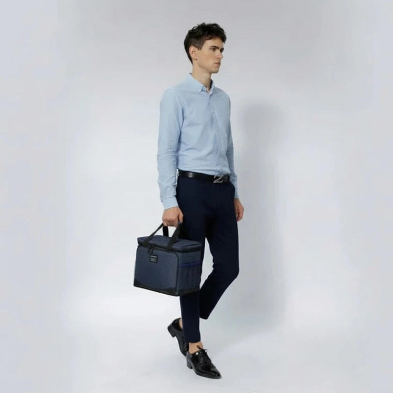 Homme en tenue professionnelle portant un sac isotherme bleu à la main, idéal pour transporter un repas au travail.