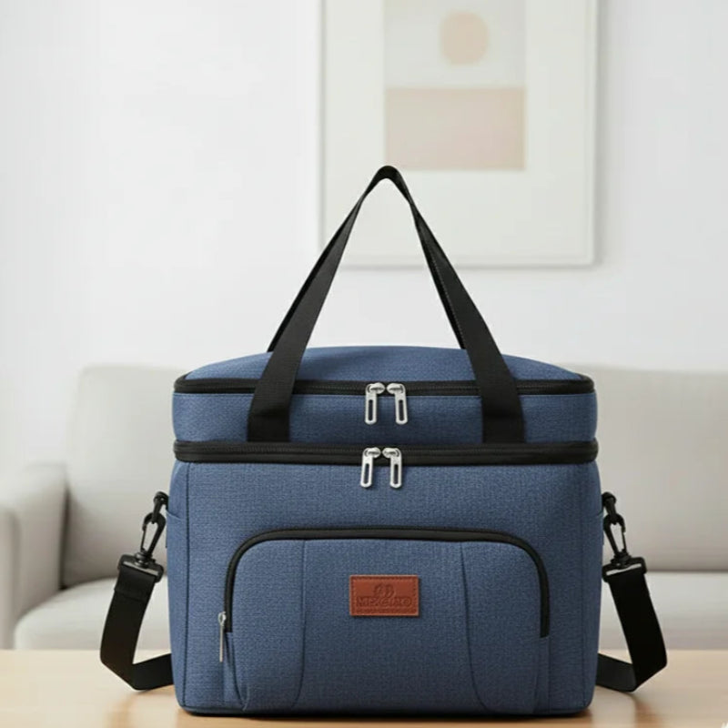 Sac isotherme repas bleu avec bandoulière et poignées noires, posé sur une table dans un intérieur moderne, idéal pour transporter déjeuner ou pique-nique.
