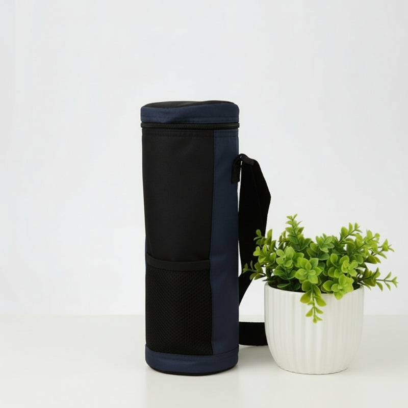 Vue latérale d’un sac isotherme bouteille bleu avec poche en maille et bandoulière, présenté sur une table blanche avec plante décorative.