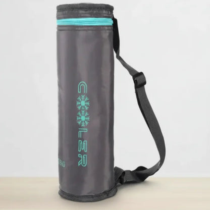 Sac isotherme bouteille gris avec bandoulière noire, posé sur une table claire devant un fond blanc épuré.