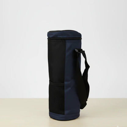 Sac isotherme pour bouteille noir et bleu vu de coter, avec sangle réglable et poche en maille, posé sur une table claire devant un fond blanc.