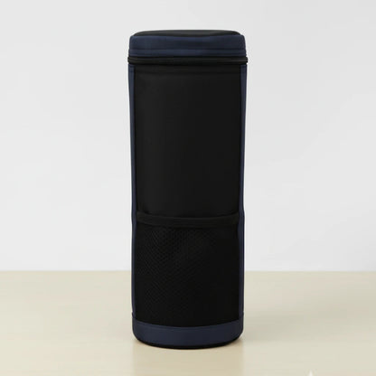Vue de face d’un sac isotherme pour bouteille noir et bleu, en tissu résistant, avec poche avant en maille, posé sur une table claire devant un fond blanc.