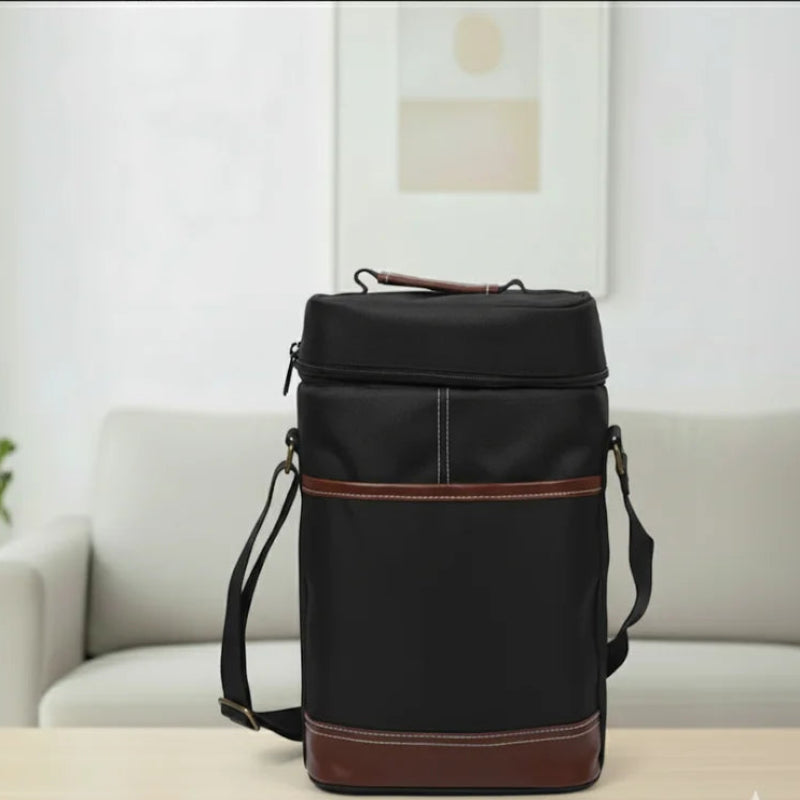 Sac isotherme bouteille noir en toile Oxford avec finitions en cuir marron, posé sur une table en bois clair de face dans un salon moderne lumineux.