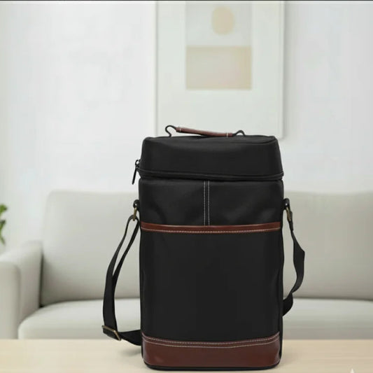 Sac isotherme bouteille noir en toile Oxford avec finitions en cuir marron, posé sur une table en bois clair de face dans un salon moderne lumineux.