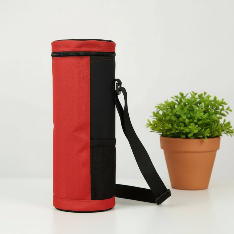 Sac isotherme pour bouteille rouge vu de côté avec bandoulière noire, posé sur une table blanche à côté d’une plante.