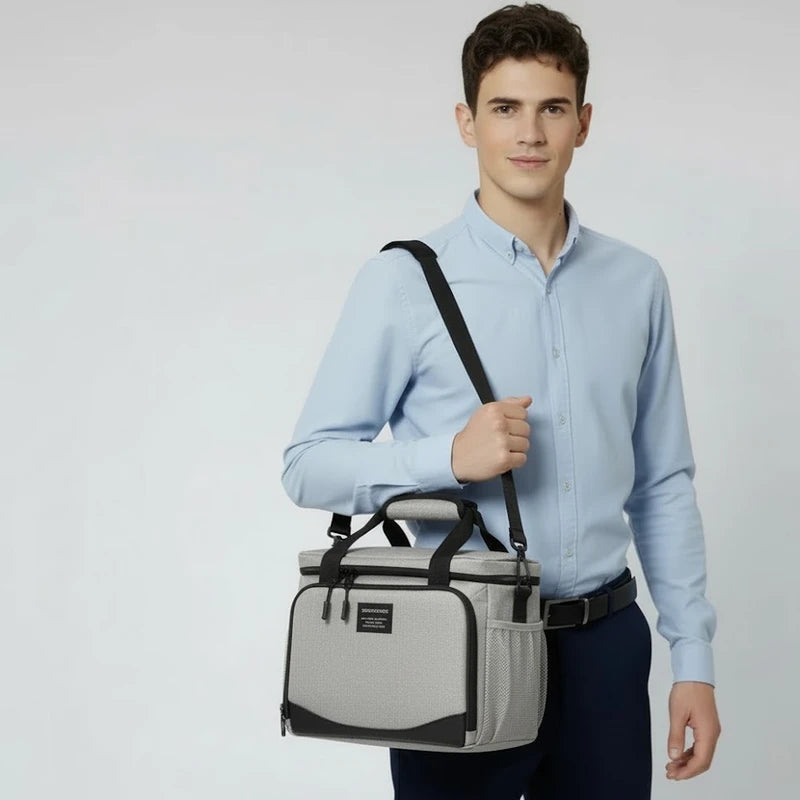 Homme en chemise claire portant un sac isotherme gris en bandoulière, idéal pour transporter un repas au travail.