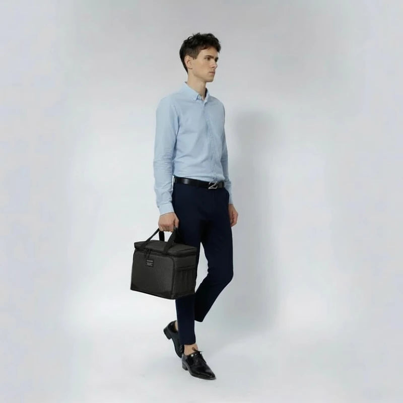 Homme habillé de manière professionnelle tenant un sac isotherme noir, idéal pour transporter un repas au travail ou en déplacement.