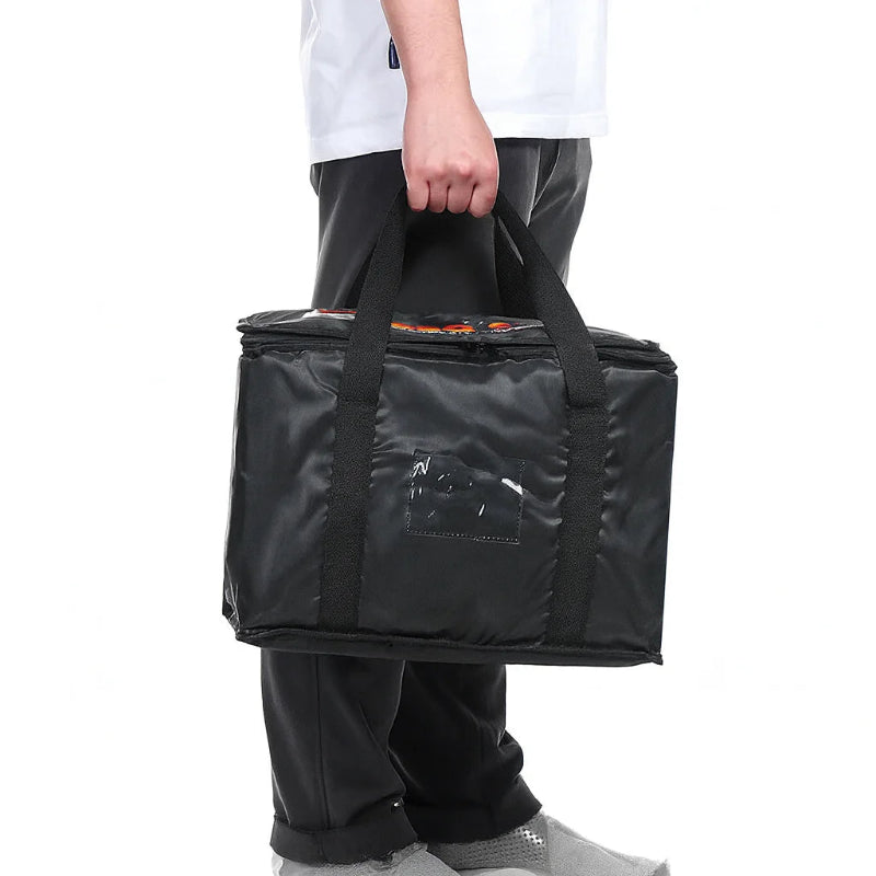 Sac isotherme noir porté à la main par une personne, adapté au transport et à la livraison de repas chauds ou froids.