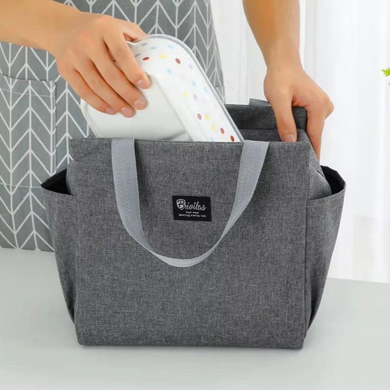 Sac isotherme repas 8L gris avec poignées, utilisé pour ranger une boîte alimentaire, doté de poches latérales, idéal pour transporter un déjeuner ou un repas du midi.