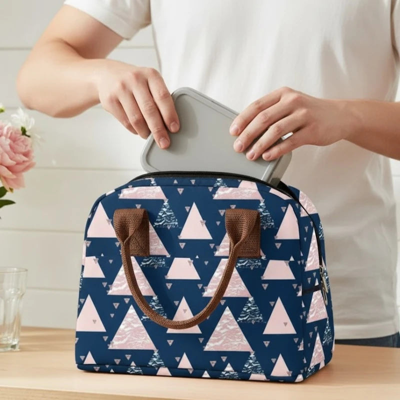 Sac isotherme motif géométrique bleu et rose, posé sur une table et utilisé pour ranger une lunch box.