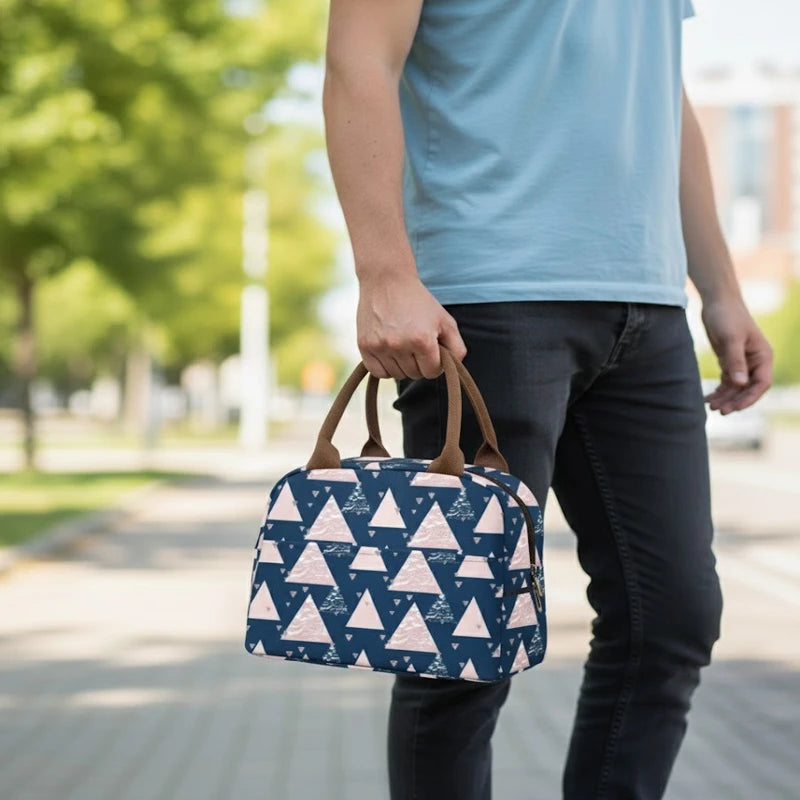 Homme marchant en extérieur avec un sac isotherme bleu à motifs géométriques rose et blanc tenu à la main.